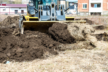 bulldozer pushes the ground, tractor pushes a lump of soil, preparing the area for construction