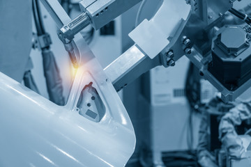 The robotics arm welding the automotive parts. The cars assembly production line.