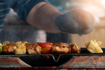 BBQ grilled on a steel grill and smoked in Thai style. Blurred of people take arms.