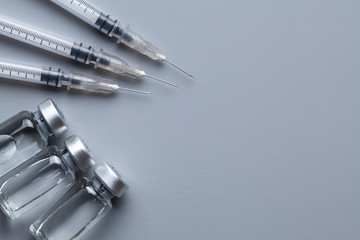 Three syringes with needles and liquid medicine in a small glass bottle