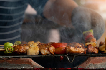 BBQ grilled on a steel grill and smoked in Thai style. Blurred of people take arms.