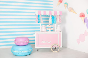 Children room with blue stripe background. candy stall photo zone with big macaroons, sweets and...