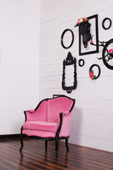 Vintage velor armchair, in a bright room. Various empty picture frames with a skull and antlers hanging on a wooden wall. The concept of wall decoration. Decor, vintage, modern, loft. Gothic style 