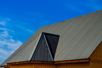 detailed roofing on a brick building under a clear blue sky; there is a lot of space for text diagonally; dark version