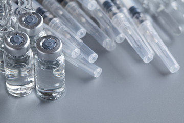 Medicines in ampoules and syringes on gray background