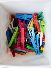 heap of colorful clothespins are lying in a box