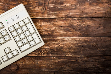 Old vintage computer keyboard on old grunge rustic dark scratched wood texture background. Text space, empty template.