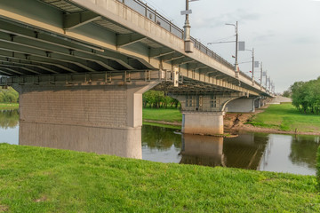 Photo of part of the bridge, the river under it in the spring time on a sunny evening