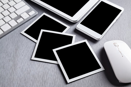 Three classic paper photo frames, mobile phone, tablet, keyboard and computer mouse