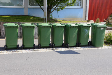 Green garbage cans are on the street