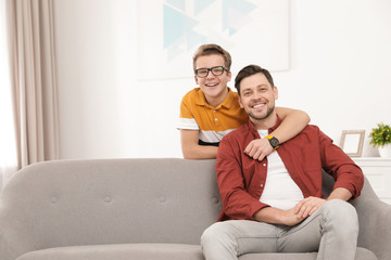 Happy teenager hugging his father at home. Space for text