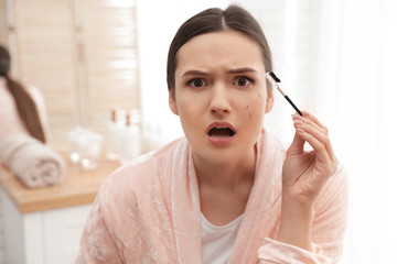 Beautiful woman with fallen eyelashes and cosmetic brush indoors