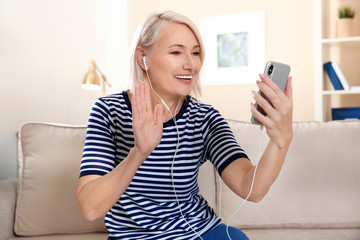 Mature woman using video chat on mobile phone at home