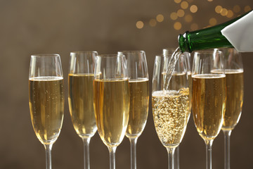 Pouring champagne into glasses on blurred background, closeup