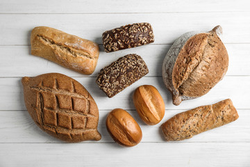 Different kinds of fresh bread on wooden table, flat lay.