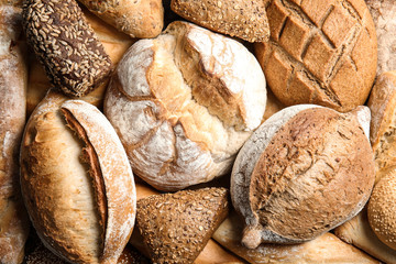 Different kinds of fresh bread as background, top view