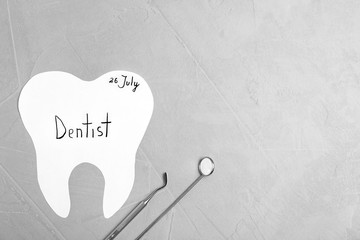 Paper tooth cutout and dentist tools on grey background, flat lay. Space for text