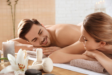 Obraz na płótnie Canvas Young couple with spa essentials in wellness center
