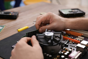Male technician repairing motherboard at table, closeup