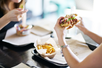 woman eating eating vegan meatless burger in restaurant