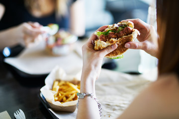 Fototapeta woman eating eating vegan meatless burger in restaurant obraz