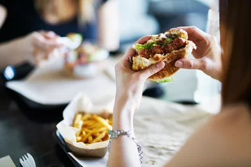Gordijnen vrouw eet veganistische vleesloze hamburger in restaurant © Joshua Resnick