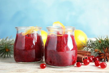 Fototapeta na wymiar Tasty cranberry sauce with citrus zest in glass jars on table