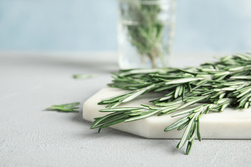 Board with fresh green rosemary twigs on table. Space for text
