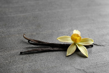 Vanilla sticks and flower on grey background. Space for text