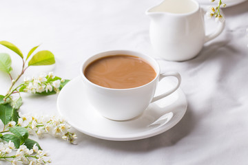 Creamy Coffee in white mug with bird-cherry tree blossom