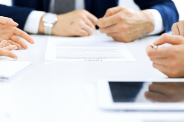 Group of business people and lawyers discussing contract papers sitting at the table, close-up. Successful teamwork, cooperation and agreement concepts