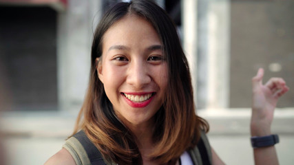 Cheerful beautiful young Asian backpacker blogger woman using smartphone taking selfie while traveling at Chinatown in Beijing, China. Lifestyle backpack tourist travel holiday concept. Point of view.