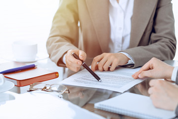 Group of business people or lawyers discussing contract papers sitting at the table, close-up