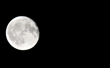 Close up of full moon with black background on left side of photo with copy space