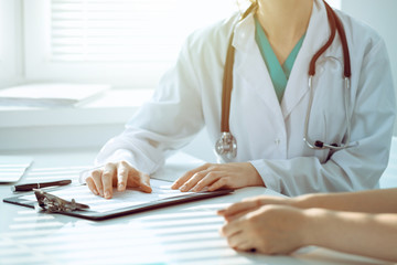 Doctor and patient are discussing something in clinic, just hands at the desk. Medicine and best service concept