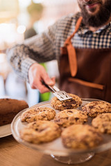  food store, the seller serves a homemade cookie to a customer