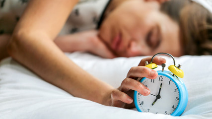 femme et son réveil dans le lit