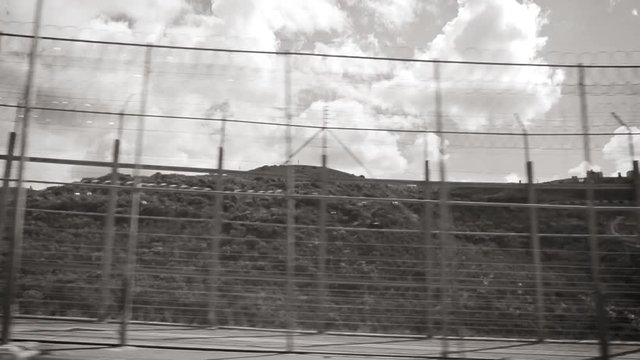 Ceuta, Spain Black and white - Footage of double barbed wire fence at Moroccan border in difficult terrain built to stop migrant inflows into EU, pushback action at border as seen from vehicle driving