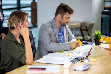 Fototapeta premium Group of happy business people men and woman working together with paper document file in meeting room.teamwork of two girl and one caucasian man discussing in office