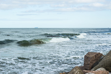 Naklejka premium Empty beach, waves and dramatic sky at the Baltic sea shore line