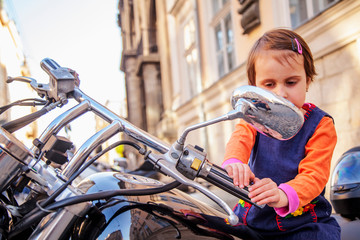 Naklejka premium Beautiful little biker child girl on a motorcycle as a symbol of freedom, adventure and travel. Humorous photography.