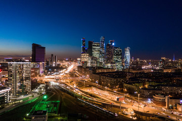 high-rise buildings and transport metropolis, traffic and blurry lights of cars on multi-lane highways and road junction at night in Moscow.