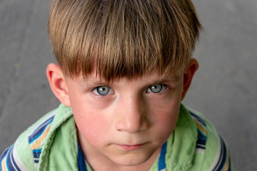 The poor and unhappy boy cries with tears in his eyes and asks for help while looking into the...