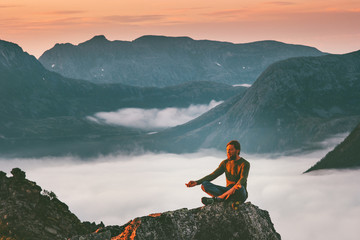 Yoga meditation in mountains man traveler  relaxing alone lotus pose above clouds summer vacations...