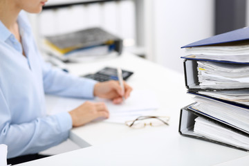 Binders with papers are waiting to be processed by business woman or bookkeeper back in blur....