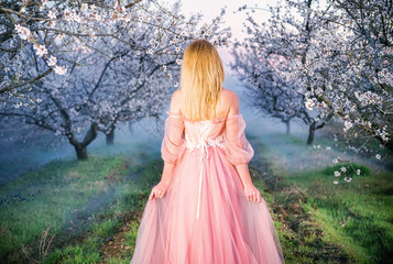 Obraz na płótnie Canvas Sevastopol, Republic of Crimea - April 1, 2019: A girl in a beautiful pink dress among flowering almond branches 