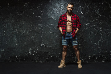 Portrait of strong healthy handsome Athletic Man Fitness Model posing near dark wall