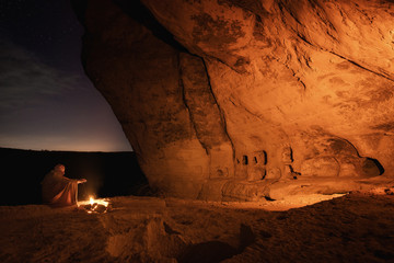 Kachi-Kalon, Bakhchysarai, Republic of Crimea, Russia - April 1, 2019: Bedouin in the Crimean cave Kachi-Kalyon is heated by the fire on the background of the starry sky