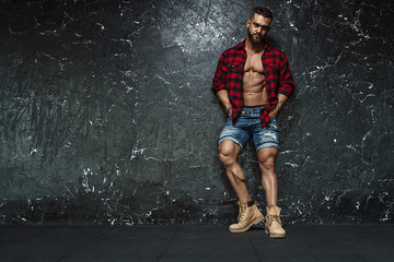 Portrait of strong healthy handsome Athletic Man Fitness Model posing near dark wall