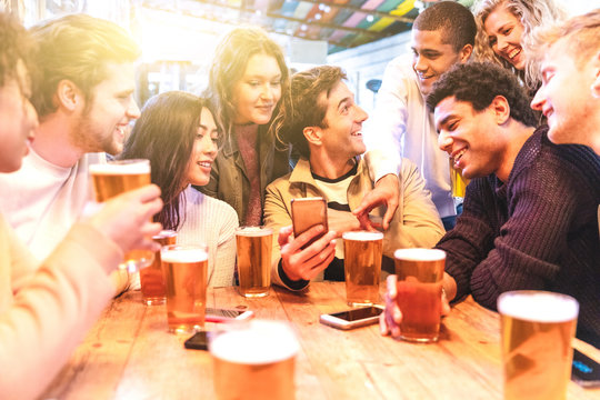 Happy millennial friends at pub drinking beer